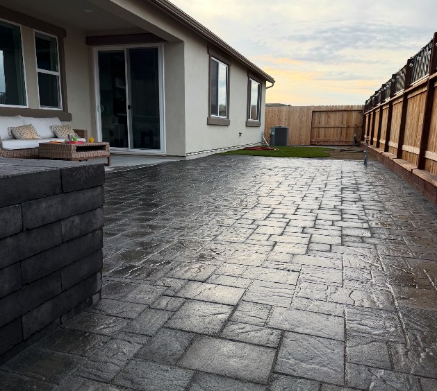Wide paver patio and driveway beside a wood fence