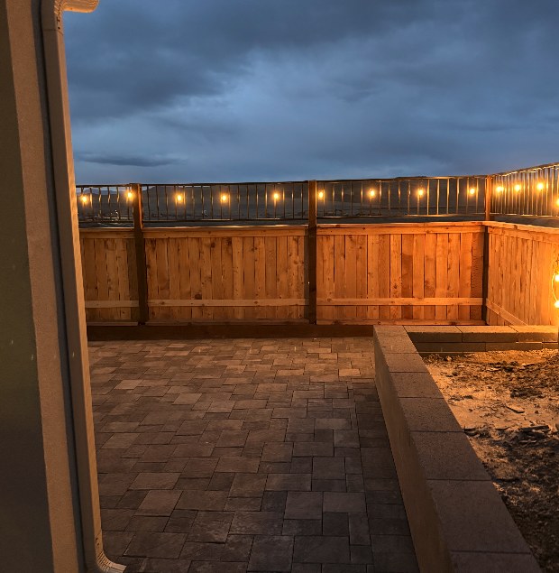Paver patio at dusk lit with string lights